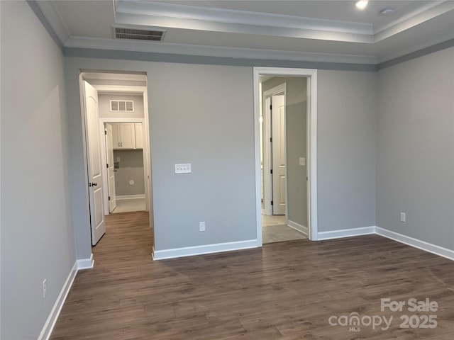 spare room featuring dark wood-type flooring, ornamental molding, and a tray ceiling