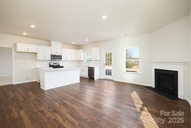 kitchen featuring white cabinets, appliances with stainless steel finishes, a kitchen island, sink, and dark hardwood / wood-style floors