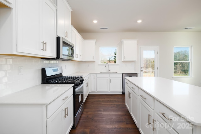 kitchen with white cabinetry, stainless steel appliances, tasteful backsplash, sink, and dark hardwood / wood-style floors