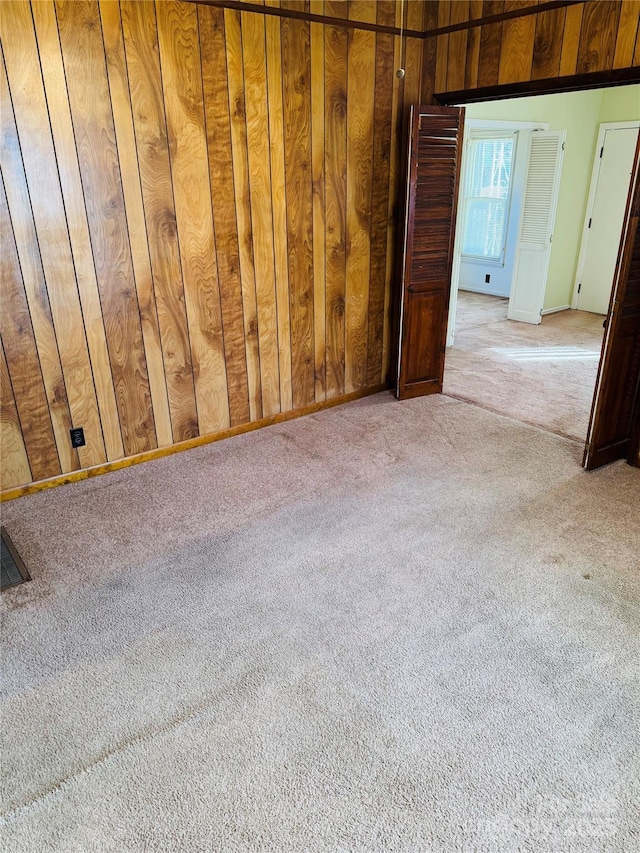 carpeted spare room with wooden walls