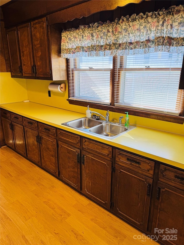 kitchen with sink, light wood-type flooring, and dark brown cabinetry