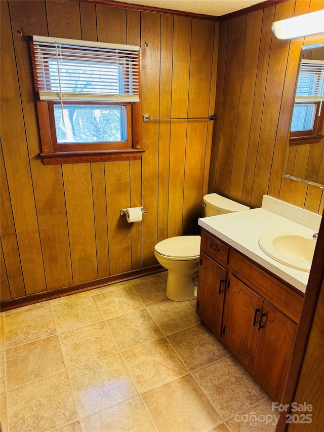 bathroom with wood walls, toilet, and vanity