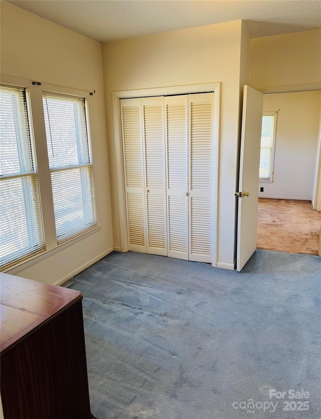 unfurnished bedroom with multiple windows, carpet, and a closet