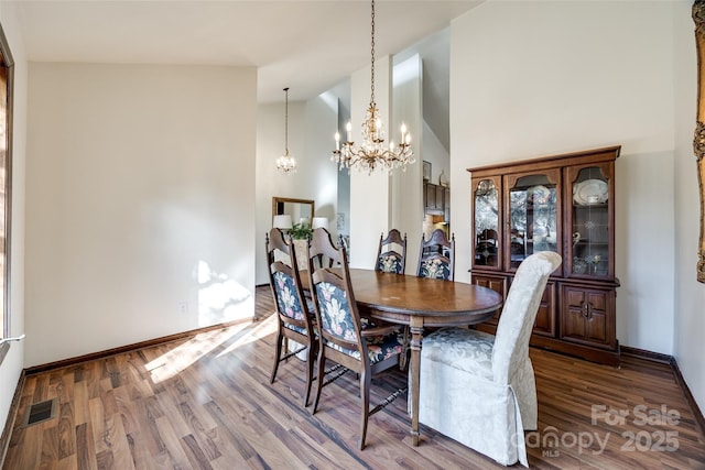 dining area with high vaulted ceiling, a chandelier, and wood-type flooring