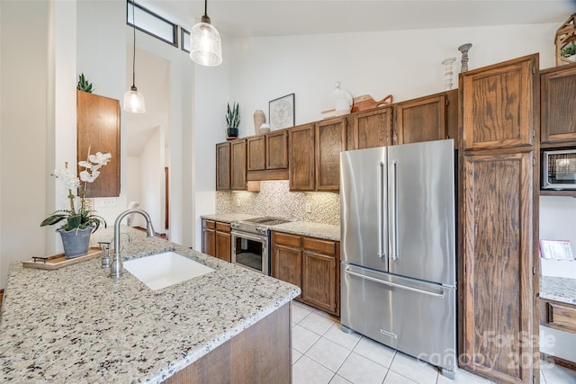 kitchen with stainless steel appliances, sink, light tile patterned floors, decorative backsplash, and hanging light fixtures