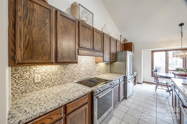 kitchen with vaulted ceiling, light tile patterned flooring, backsplash, hanging light fixtures, and appliances with stainless steel finishes