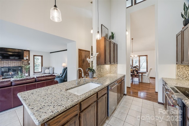 kitchen with sink, stainless steel appliances, decorative light fixtures, light tile patterned flooring, and tasteful backsplash