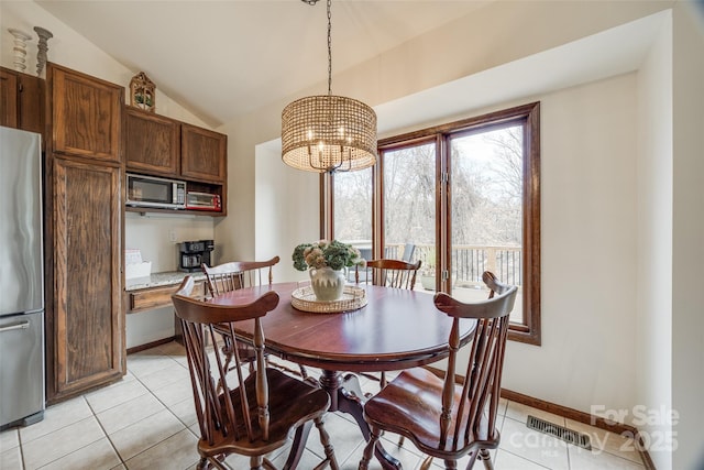 dining room featuring vaulted ceiling and light tile patterned flooring