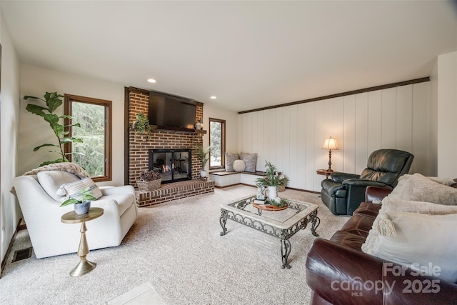 carpeted living room featuring a fireplace and wooden walls