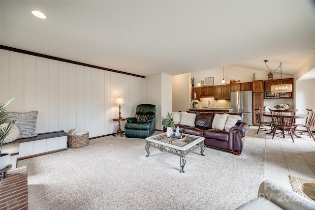 carpeted living room with lofted ceiling and an inviting chandelier