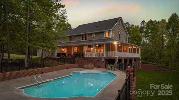 back house at dusk with a patio area and a fenced in pool