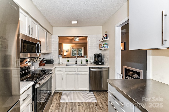 kitchen featuring decorative backsplash, sink, white cabinetry, appliances with stainless steel finishes, and a textured ceiling