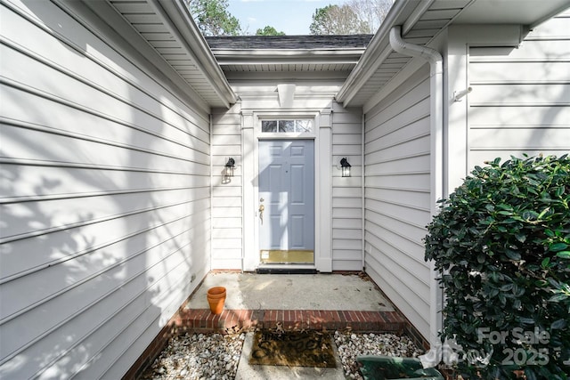 entrance to property featuring a shingled roof