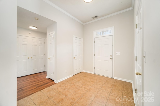 entrance foyer featuring light tile patterned floors, visible vents, crown molding, and baseboards