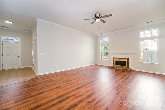 unfurnished living room featuring a fireplace, wood finished floors, baseboards, and ornamental molding