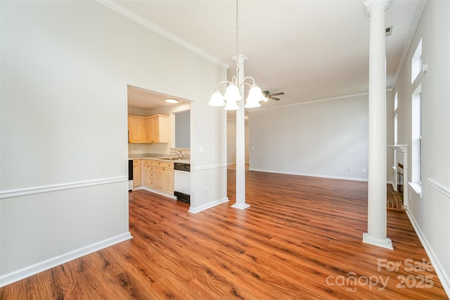 unfurnished dining area featuring baseboards, ornamental molding, decorative columns, wood finished floors, and a sink