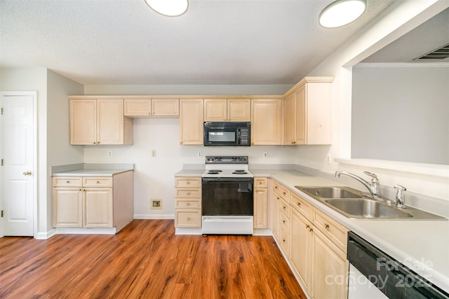 kitchen featuring wood finished floors, white range with electric cooktop, a sink, black microwave, and dishwasher