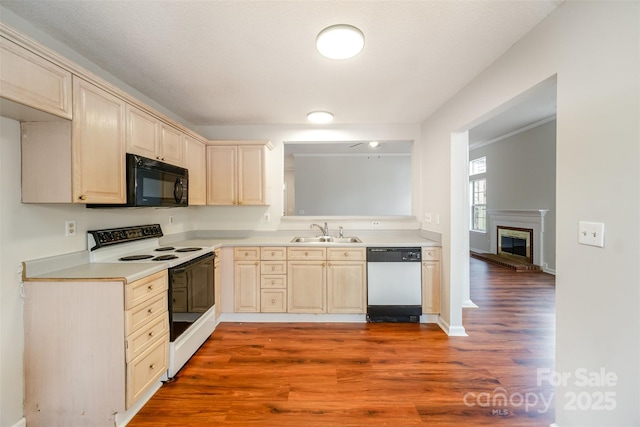 kitchen with black microwave, dishwasher, light countertops, electric range, and a sink