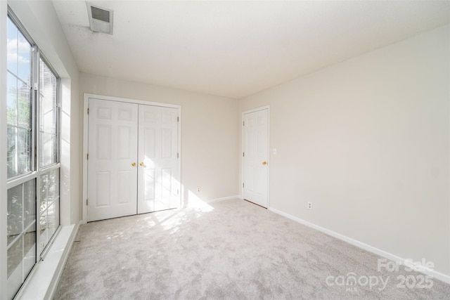 unfurnished bedroom featuring visible vents, baseboards, carpet, and a closet