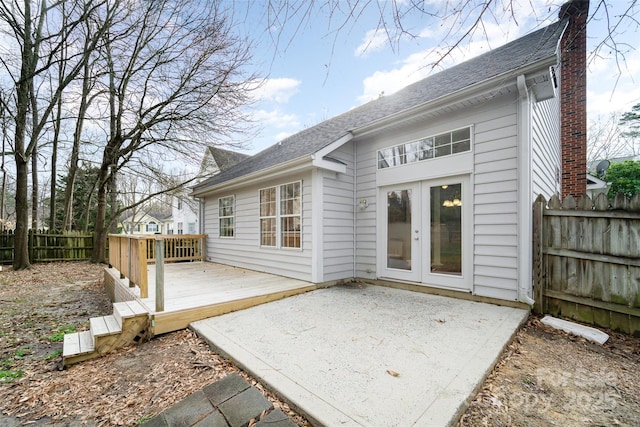 back of property with french doors, a chimney, a deck, and fence