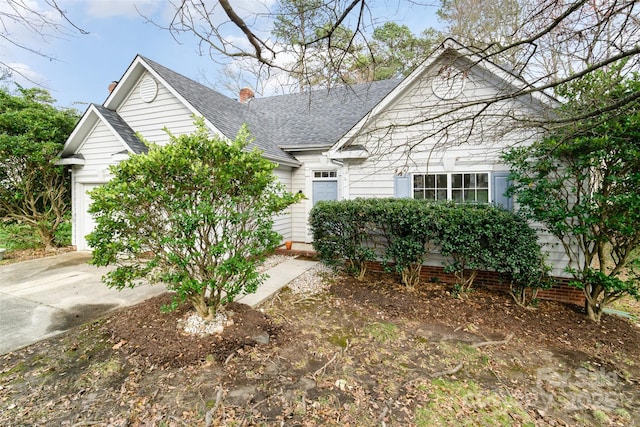 view of front of house featuring concrete driveway, an attached garage, roof with shingles, and a chimney