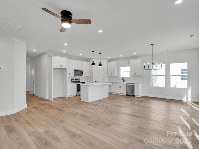 kitchen with stainless steel appliances, white cabinetry, a kitchen island, and pendant lighting