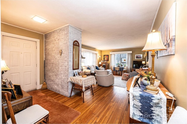 living room with brick wall, crown molding, and hardwood / wood-style floors