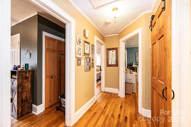 hall featuring a textured ceiling, ornamental molding, and light hardwood / wood-style floors