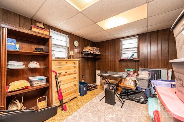 interior space with a paneled ceiling and wood walls