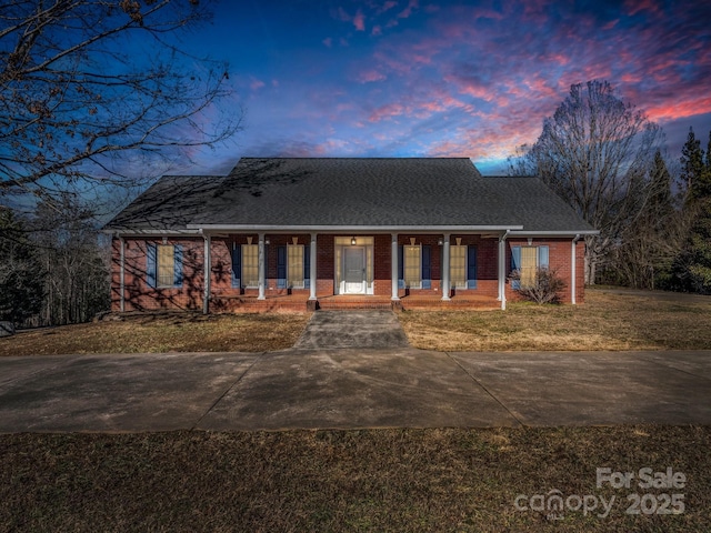 ranch-style house featuring covered porch and a yard