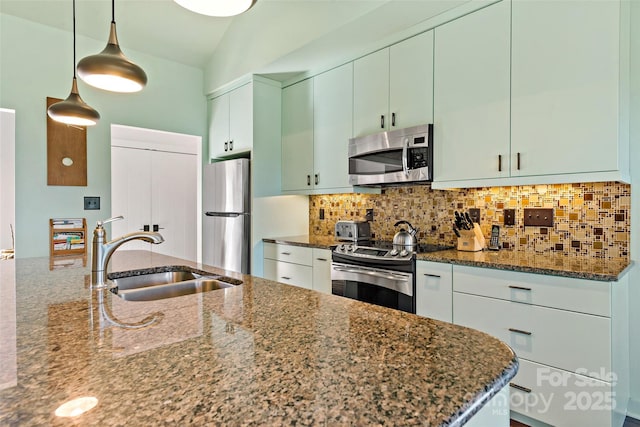 kitchen featuring appliances with stainless steel finishes, decorative light fixtures, dark stone counters, tasteful backsplash, and sink