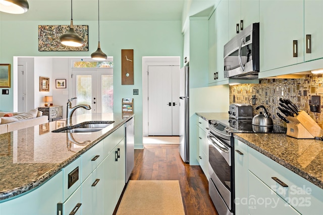 kitchen with stainless steel appliances, dark hardwood / wood-style flooring, dark stone counters, pendant lighting, and sink