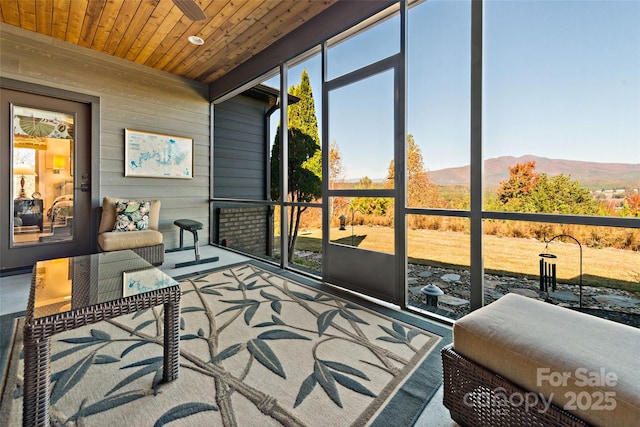 sunroom / solarium with wood ceiling, plenty of natural light, and a mountain view