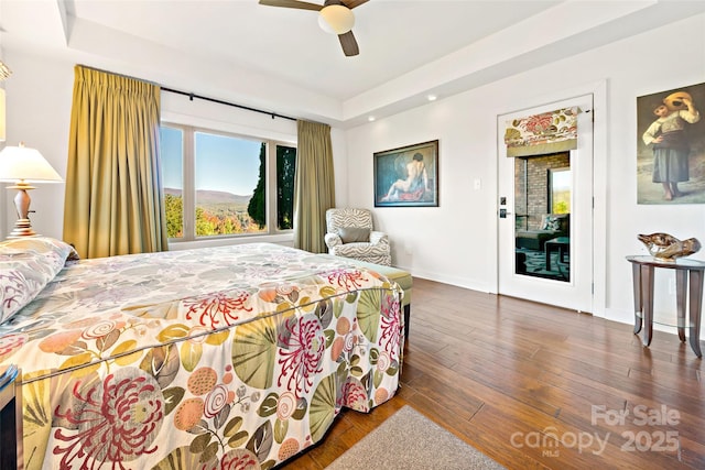 bedroom featuring ceiling fan, a tray ceiling, and dark hardwood / wood-style flooring