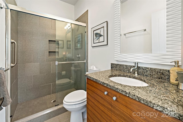 bathroom with toilet, tile patterned floors, a shower with shower door, and vanity