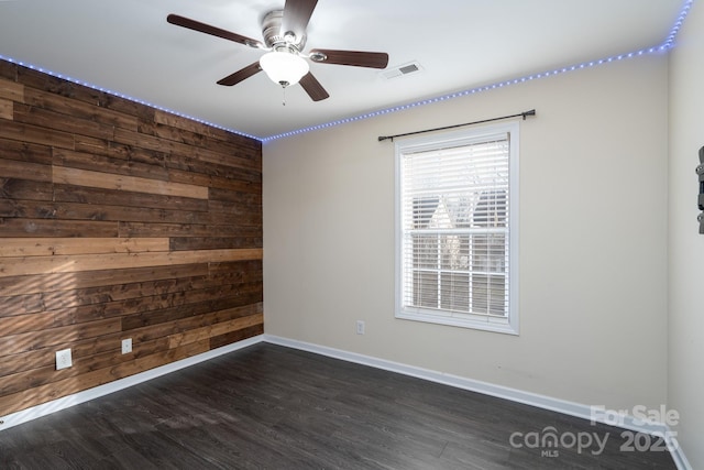 spare room with ceiling fan, dark hardwood / wood-style flooring, and wood walls