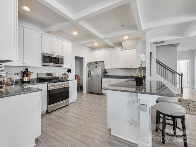 kitchen featuring appliances with stainless steel finishes, white cabinetry, beam ceiling, coffered ceiling, and light hardwood / wood-style floors