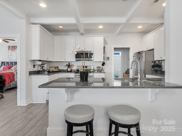 kitchen featuring coffered ceiling, appliances with stainless steel finishes, kitchen peninsula, beam ceiling, and white cabinets