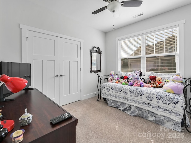 bedroom with light colored carpet, ceiling fan, and a closet