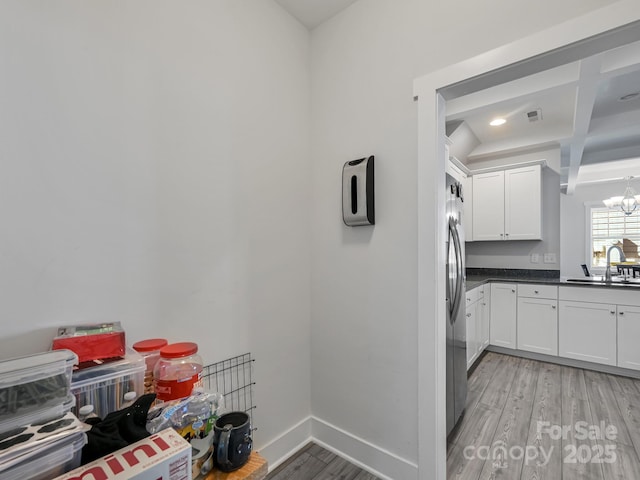 kitchen featuring stainless steel refrigerator, white cabinetry, sink, a chandelier, and light hardwood / wood-style floors