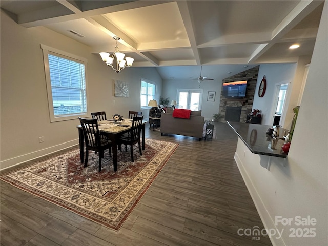 dining space featuring dark wood-type flooring, coffered ceiling, beam ceiling, a fireplace, and ceiling fan with notable chandelier