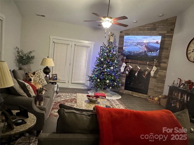 living room with lofted ceiling, a large fireplace, and ceiling fan