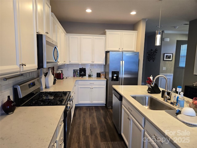 kitchen with appliances with stainless steel finishes, white cabinetry, hanging light fixtures, decorative backsplash, and sink