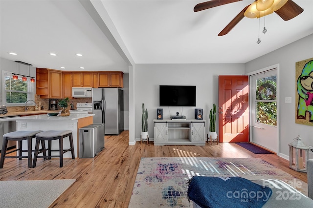 living room with light wood-type flooring, ceiling fan, and sink