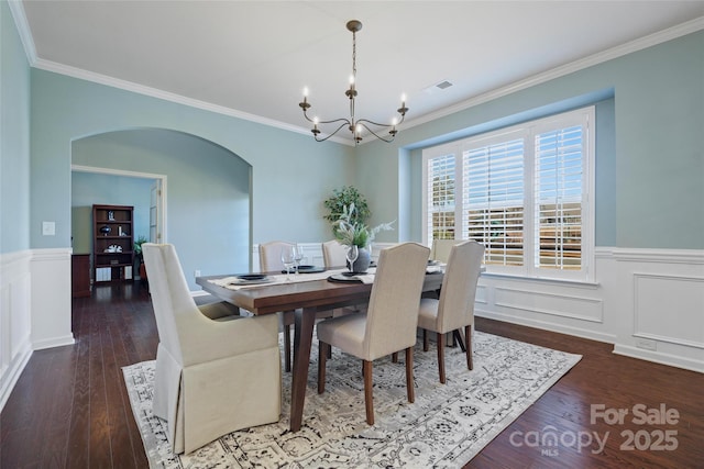 dining area featuring crown molding, dark hardwood / wood-style floors, and a notable chandelier