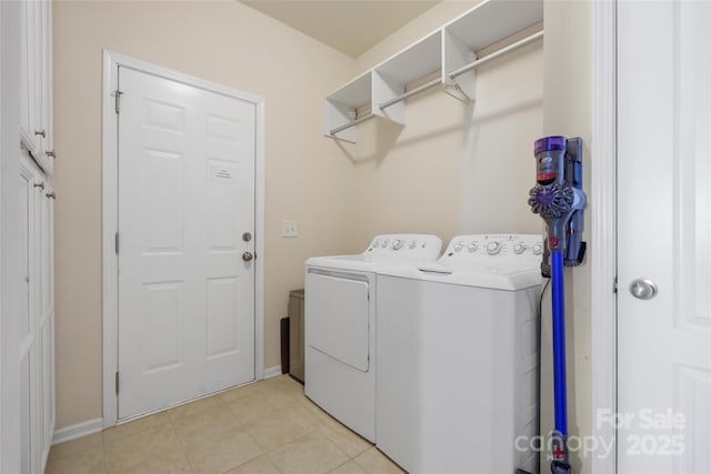 clothes washing area with cabinets, separate washer and dryer, and light tile patterned floors