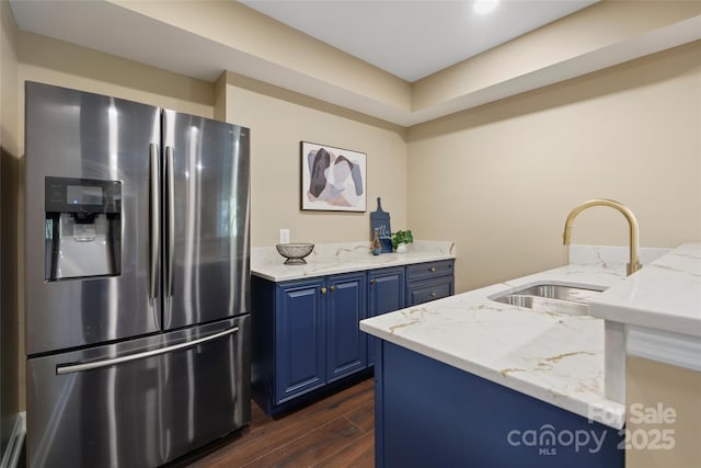 kitchen with blue cabinets, sink, dark hardwood / wood-style floors, stainless steel fridge, and light stone countertops