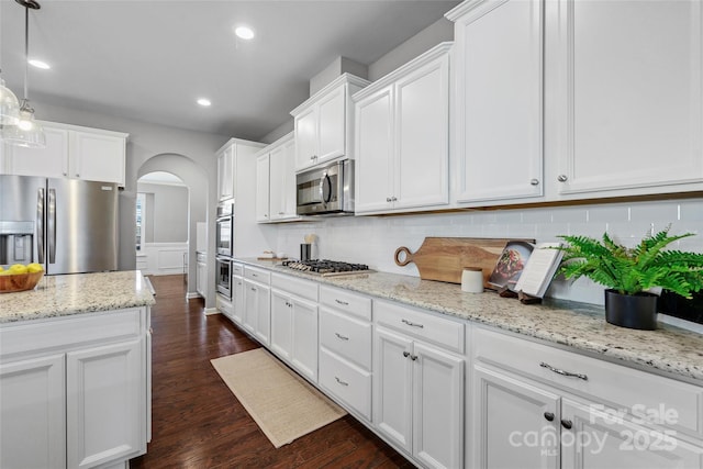 kitchen with white cabinetry, stainless steel appliances, decorative backsplash, dark hardwood / wood-style flooring, and decorative light fixtures