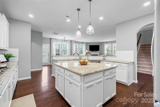 kitchen featuring a kitchen island, dark hardwood / wood-style floors, pendant lighting, refrigerator, and white cabinetry