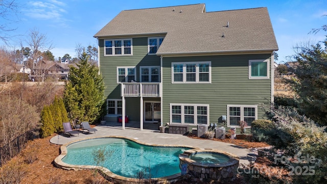 rear view of house with a pool with hot tub, a patio, and a balcony